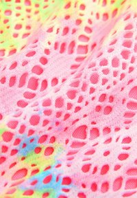 Tissu en tricot rose avec un motif en dentelle et un tissage ouvert, mettant en valeur des accents de tie-dye colorés dans des teintes de vert et de bleu.