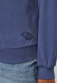 Blauwe sweatshirt met geribbelde zoom en boorden, met een geborduurd logo in marineblauw. Gemaakt van zachte stof, met een casual ontwerp.