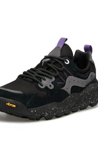 Scarpe sportive nere con una combinazione di materiali in suede e rete, accenti grigi, dettagli viola e una suola maculata. Presentano un laccio intricato.