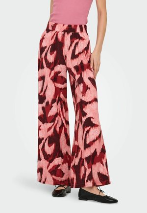 Pantalons larges à motif abstrait multicolore avec des teintes de rouge et de rose, fabriqués en tissu léger avec une taille élastique.