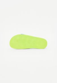 Suola in gomma verde brillante con un motivo testurizzato di esagoni, caratterizzata da una forma arrotondata e bordi lisci, progettata per la trazione.