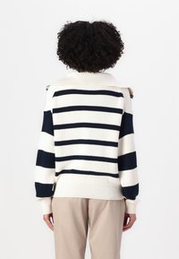 Pulover tricotat în dungi, de culoare crem și bleumarin, cu guler înalt, mâneci lungi și manșete canelate. Design simplu, fără embellishements suplimentare.