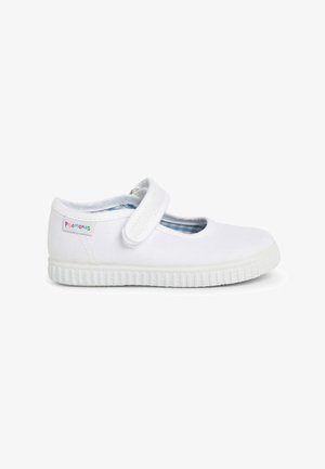 Zapatilla de lona blanca con punta redonda, correa elástica y suela de goma texturizada. Presenta un forro a cuadros azul y un pequeño parche con logo.