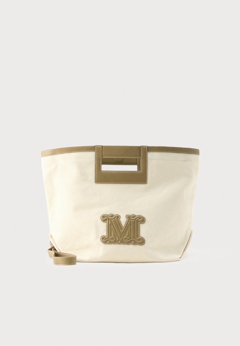 Μπεζ πάνινη τσάντα ώμου με καφέ δερμάτινες λεπτομέρειες, ορθογώνιες κομμένες λαβές, αφαιρούμενο ιμάντα και διακοσμητικό ανάγλυφο γράμμα "M" μπροστά.