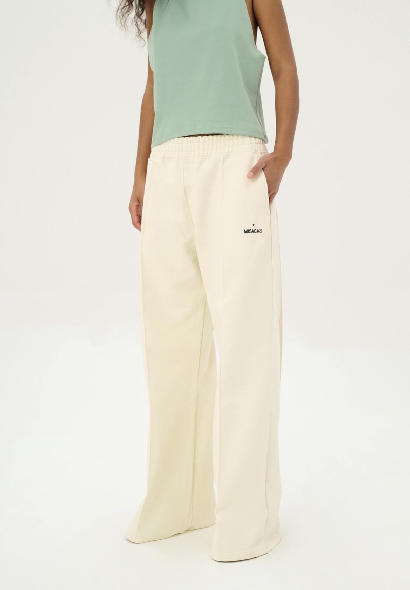 Crèmekleurige wijde sweatpants met een elastische tailleband en zijzak, met het merklogo "MISAGA" in het zwart aan de linkerkant.