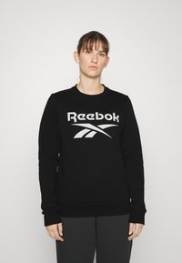 Felpa nera con scollo a girocollo, maniche lunghe e un grande logo grigio Reebok sul davanti. Presenta un orlo e polsini a coste.