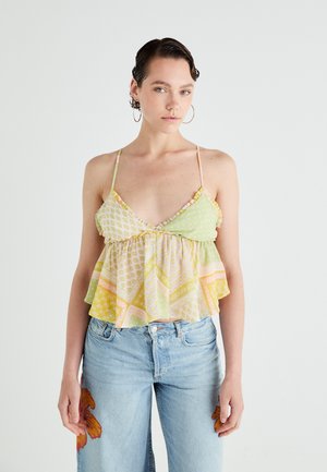Bloemmotief, lichte stoffen top in groen, geel en roze. Heeft een gerimpelde zoom en dunne bandjes, gecombineerd met lichtblauwe denim jeans.
