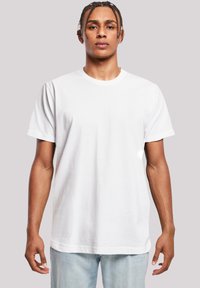 White cotton t-shirt with a round neck and short sleeves, featured on a model against a neutral background, showing a relaxed fit.