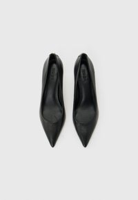 Paire d'escarpins en cuir noir à bout pointu avec la marque "HUGO" à l'intérieur, vus de dessus sur un fond blanc uni.