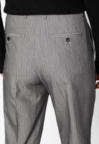 Harmaat raitahousut, joissa on sileä pinta, kaksi takataskua napillisin sulkumekanismein ja istuva malli.