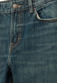 Jeans iz temno modrim pranjem, z svetlo rjavimi šivi, klasičnim gumbom za zapiranje in subtilnimi detajli na žepih.