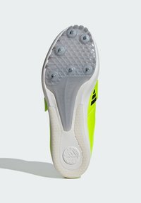 Scarpa da ginnastica verde con suola bianca texture e sei borchie argentate. Logo nero audace visibile sul lato.