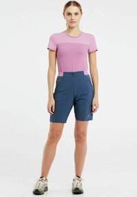 Růžový krátký rukáv top s texturovaným panelem na hrudi, spárovaný s modrými šortkami s vysokým pasem, bočními kapsami na zip a hladkým povrchem.