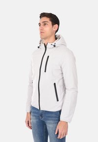Giacca leggera bianca con cappuccio e accenti neri. Presenta tasche con zip e cordini regolabili sul cappuccio. Tessuto morbido.
