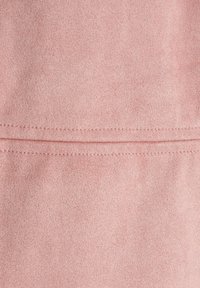 Tissu en suédine synthétique rose clair avec une texture douce, présentant un détail de couture horizontale pour un élément de design supplémentaire.