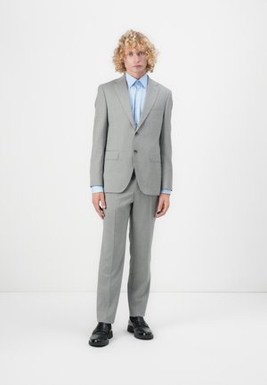 Gray suit made from textured fabric; features a single-breasted jacket, notch lapels, and matching trousers paired with a light blue shirt and black shoes.