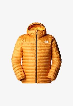 Geel geïsoleerd jack met horizontale quilt, rits aan de voorkant en een capuchon. Bevat een logo op de linkerborst en elastische manchetten.