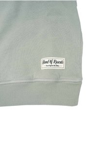 Felpa verde chiaro con polsini a coste. Presenta un'etichetta bianca con "Band of Rascals" e della scritta, realizzata in un morbido cotone.