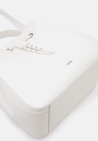 Bolso tote de cuero blanco con un acabado texturizado, que presenta una base plana, un lazo de cordón, acentos de hardware plateado y un detalle sutil del logotipo.