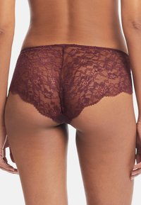 Burgundy spetsshorts har en scalloped kant, intrikata blommönster och genomskinligt material, vilket ger en delikat look med mjuk textur.