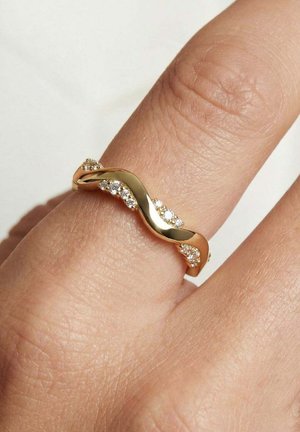 Guld snoet båndring med små diamanter båret på en finger, der fremhæver de glitrende sten og den glatte gyldne finish.