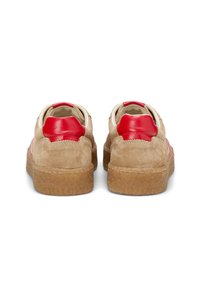 Sneakers in suede beige con dettagli in pelle rossa, suola in gomma testurizzata, forma arrotondata e fodera morbida. Cuciture visibili lungo i bordi.