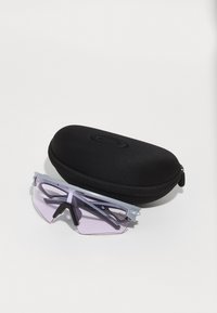 Sonnenbrille mit einem grauen Gestell und pink getönten Gläsern, die neben einem schwarzen Reißverschluss-Hardcase mit glatter Oberfläche liegt.