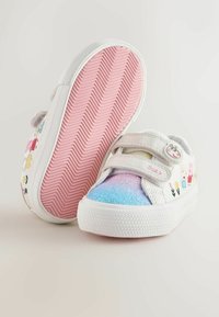 White sneakers with colorful character prints, glitter gradient toe, and Velcro straps. Textured rubber sole with pink herringbone pattern.