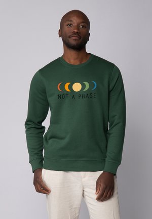 Groene sweatshirt met ronde hals, voorzien van een grafiek met gekleurde maanfasen en de tekst "GEEN FASE" in het zwart eronder.