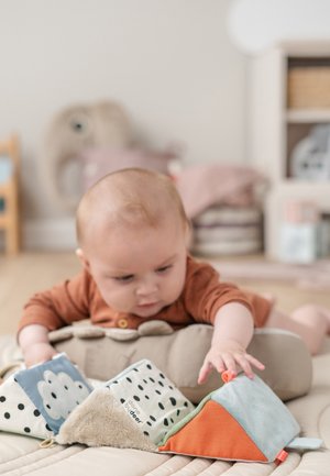 Zachte knuffeldieren in verschillende vormen en kleuren: blauw, groen, oranje en stoffen met patronen en textuurelementen. Lichtgekleurde speelmat.