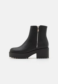 Botas negras hasta el tobillo con punta redonda, de cuero sintético texturizado, cremallera lateral y suela de plataforma gruesa con ranuras de tracción.