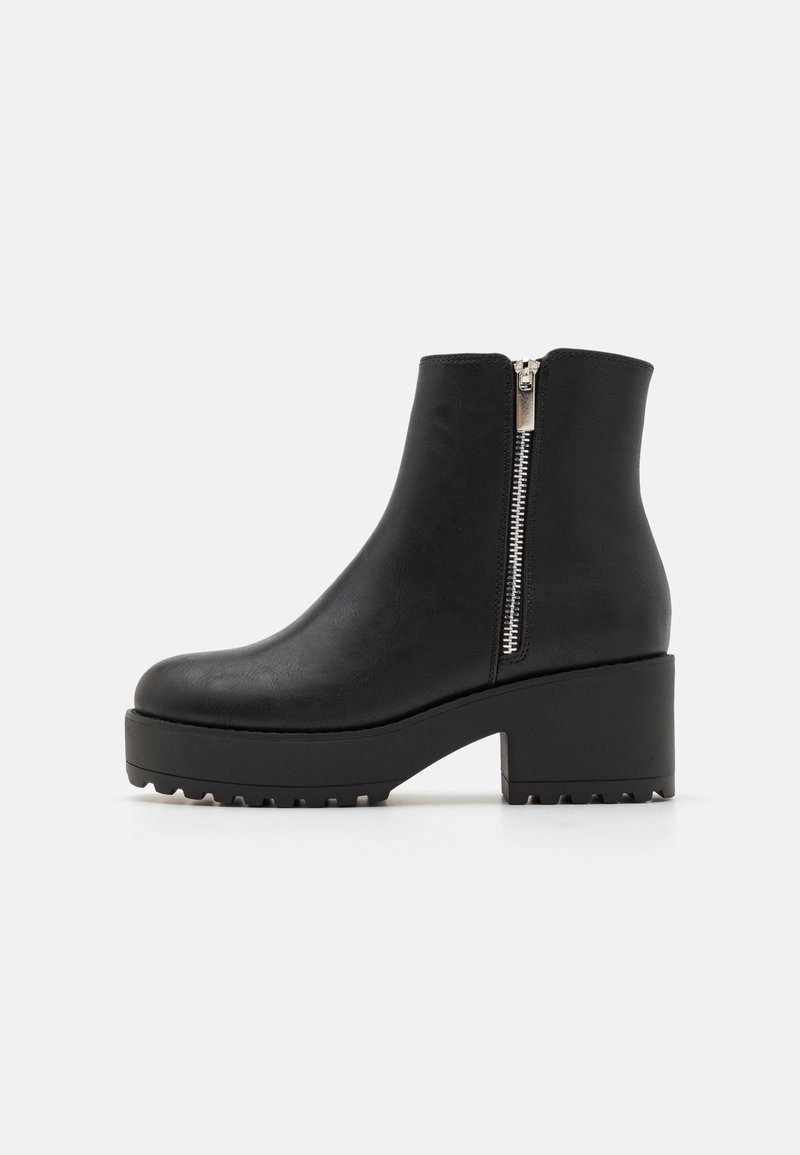 Botas negras hasta el tobillo con punta redonda, de cuero sintético texturizado, cremallera lateral y suela de plataforma gruesa con ranuras de tracción.