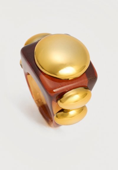 Χονδρό διάφανο καφέ δαχτυλίδι με ένα μεγάλο και τέσσερα μικρότερα λαμπερά χρυσά κυκλικά διακοσμητικά.