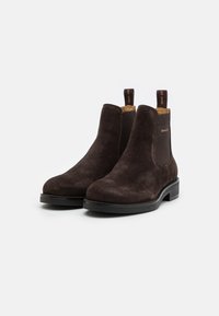 Bottes Chelsea en daim marron avec panneaux latéraux élastiques, bout arrondi et languette de tirage. Semelle en caoutchouc noir durable et détails subtils de logo.