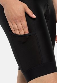 Zwarte sportshorts met een gladde, rekbare textuur en een zijzak. Beschikt over platte naden en een aansluitend ontwerp.