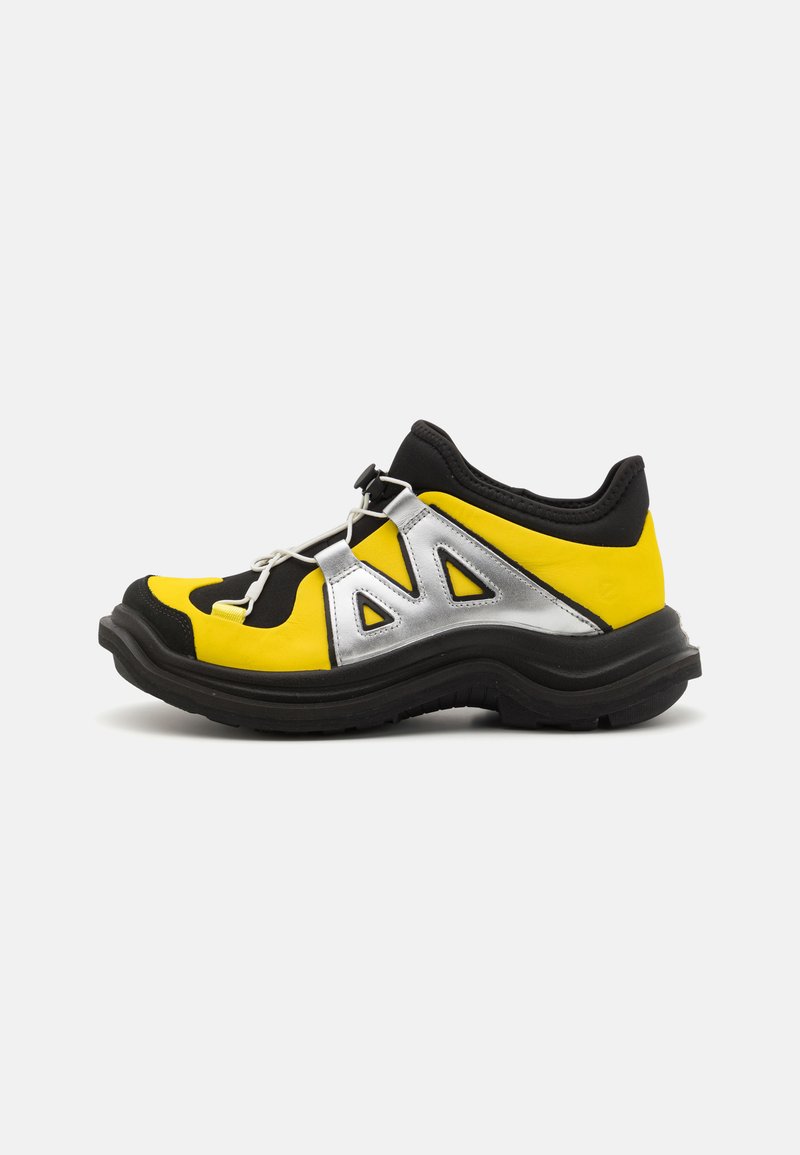 Yellow and black sneakers with silver accents, featuring a chunky black sole, cut-out design, and elastic lacing system for secure fit.