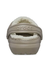 Beige Crocs met een fuzzy witte voering en een achterste schakel. Geef de bovenkant een structuur met een gladde afwerking. Kenmerkt zich door het onderscheidende Crocs-logo.