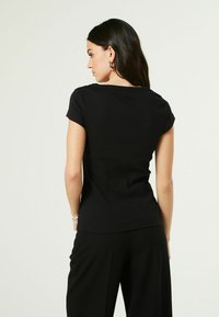 Černé přiléhavé tričko s krátkým rukávem, vyrobené z žebrované tkaniny, s kulatým výstřihem a hladkým, elegantním designem.