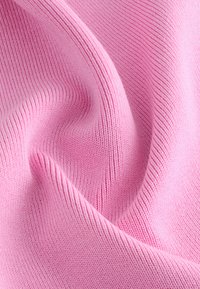 Tela de punto rosa con una textura fina de canalé, que muestra un material suave y liso con un brillo sutil y una caída delicada.