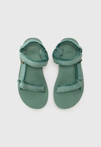 Green fabric sandals with adjustable straps, flat soles, and a contoured footbed. Textured accents on strap edges for grip.