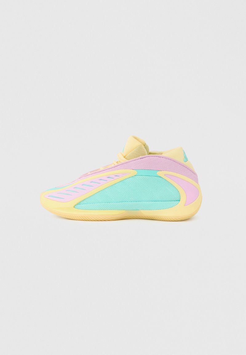 Baskets basses avec semelle jaune pastel, dessus en mesh rose et turquoise, et languette jaune, vues de profil sur un fond uni.