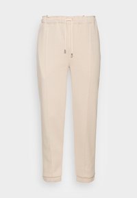 Light beige sweatpants with a drawstring waist, tapered fit, cuffed hems, and vertical side seams. Made from a soft, textured material.