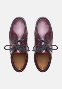 Burgunderfarbene Lederschuhe mit glänzender Oberfläche, runder Zehenform und schwarzen Schnürsenkeln. Mit goldenen Ösen und einer gesteppten Kante entlang der Seite.