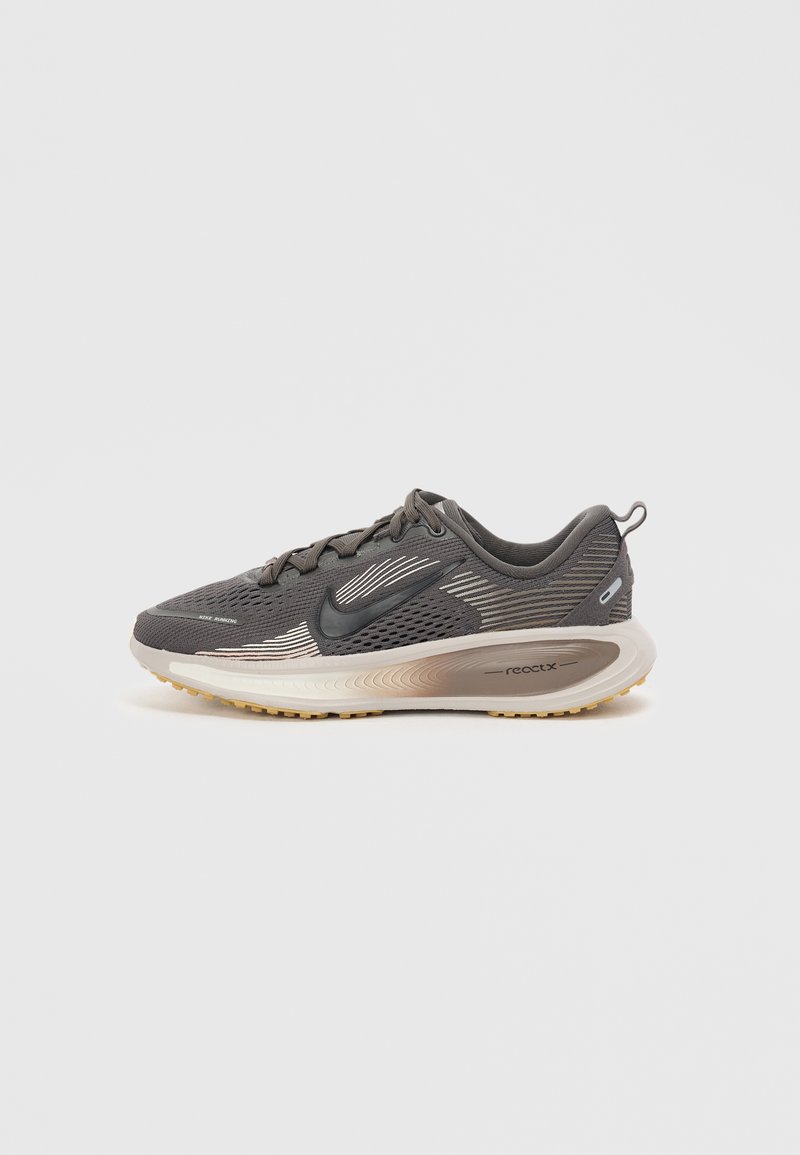 Scarpe sportive in rete grigia scura con dettagli neri, dotate di una suola imbottita beige e un design elegante e leggero. Marchio ben visibile di lato.