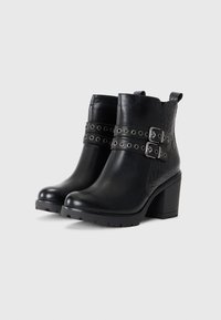 Black ankle boots with a textured croc pattern, two strap buckles and metal eyelets. Chunky heel with a rubber sole for grip.