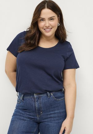 Marineblaues Kurzarm-T-Shirt mit Rundhalsausschnitt, aus weichem Stoff gefertigt. Kombiniert mit dunkelblauen Jeans aus Denim, die ein klassisches Fünf-Taschen-Design aufweisen.