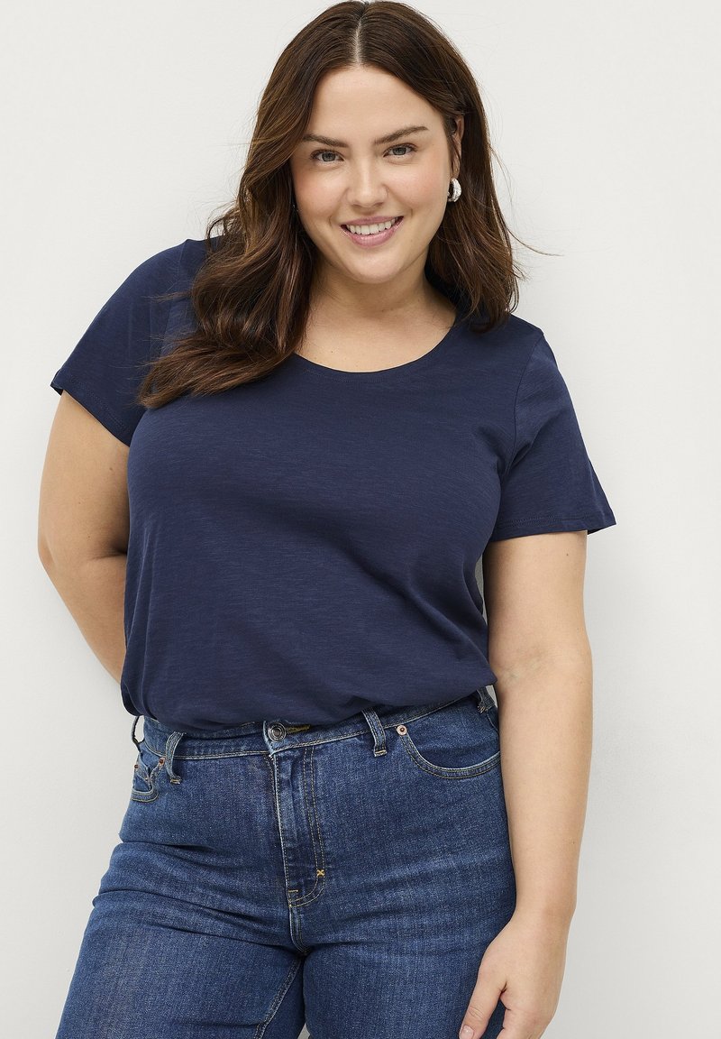 T-shirt blu navy a maniche corte con scollatura rotonda, realizzato in tessuto morbido. Abbinato a jeans in denim blu scuro, caratterizzati da un design tradizionale a cinque tasche.