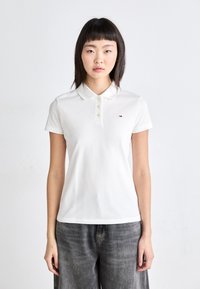 Polo blanc à manches courtes, avec patte de boutonnage à trois boutons et petit logo sur le côté gauche de la poitrine. Tissu en mélange de coton avec texture lisse.