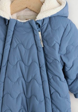 Blaue gesteppte Jacke mit Kapuze, ausgestattet mit einem weichen, cremefarbenen Fleecefutter und einem wellenförmigen Stichmuster. Mit Reißverschluss und Aufhänger-Details.