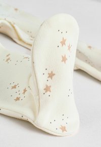 Chaussettes couleur crème présentant un motif d'étoiles avec des points marron et gris, texture douce et design côtelé sur la partie supérieure.
